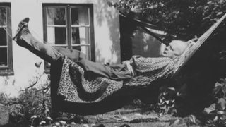 Ein mann liegt in einer Hängematte in einem Kleingarten auf einem alten Bild von früher. 