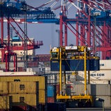 Das Bild zeigt mehrere Containerbrücken, Container-Kräne und Container.
