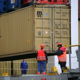 Hafenarbeiter stehen an einem Container in Bremerhaven.