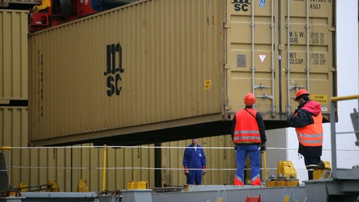 Hafenarbeiter stehen an einem Container in Bremerhaven.