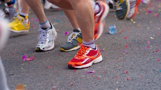 Mehrere Menschen rennen bei einem Laufwettbewerb über Asphalt.