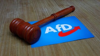 Ein Richterhammer liegt auf einem AfD-Schild.