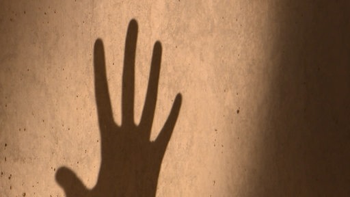 Ein Schatten einer Hand auf einer Wand.