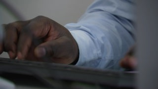 Eine Nahaufnahme einer Hand, die auf einer Tastatur liegt.