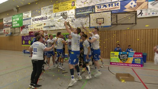 Das Handball-Team des ATSV Habenhausen feiert seinen Sieg mit einem Pokal.