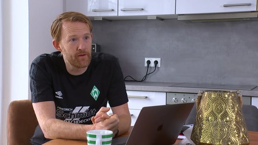 Werder-Handballtrainer Robert Nijdam im Interview in einer Küche. Er sitzt vor einem Laptop.