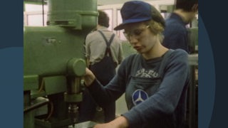 Eine jugendliche Frau steht an einer Metallbohrmaschine