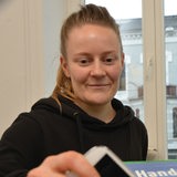 Blonde Frau, Anfang 30, steckt Handy in eine Sammelbox