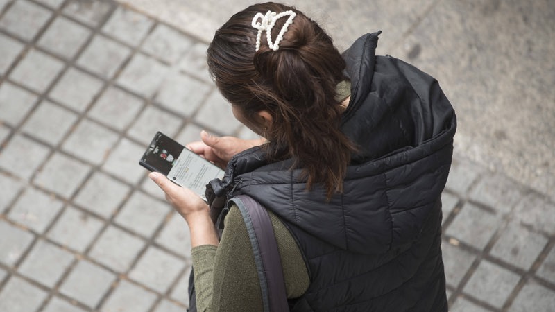 Eine junge Frau tippt auf ihr Smartphone