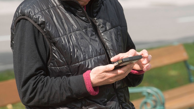 Eine Frau tippt auf ihrem Smartphone (Symbolbild)