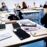 Zahlreiche Smartphones liegen in der Schule auf einem Tisch, die die Schüler abgeben mussten.