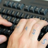 Hände über einer Computertastatur, auf einer Hand steht das Wort "Hass" auf den Fingern. (Symbolbild)