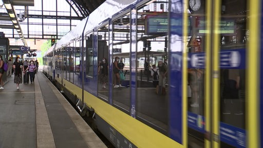 Ein Bahnsteig auf dem Bremer Hauptbahnhof in dem gerade ein Zug der Nordwest-Bahn einfährt. Passagiere stehen davor und warten.