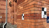 Plakate mit einem Karomuster hängen an einer Außenwand des Bahnhofs.