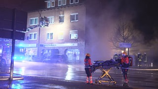 Retter arbeiten im Rauch eines Feuers. Beim Brand eines Wohnhauses in Twistringen im Kreis Diepholz sind mindestens drei Menschen verletzt worden. 