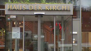 Das Eingangsportal eines Gebäudes, über dessen Tür der Schriftzug Haus der Kirche angebracht ist