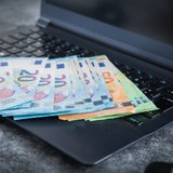 Geldscheine liegen auf einem Laptop.