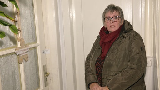 Die Hausverwalterin Heike Wotjes steht vor der geschlossenen Wohnungstür. 