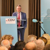 Ein Mann steht an einem Pult vor Zuhörern