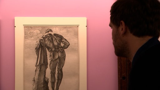Ein Mann schaut auf die künstlerische Darstellung eines Helden. 