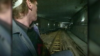 Zu sehen ist ein Arbeiter, welcher durch den sich im Bau befindenden Hemelinger Tunnel fährt.