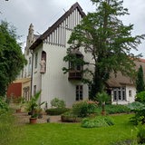Vor einer alten Villa liegt ein Garten mit einer Statue.
