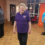 Hilde Tscharntke steht mit einem lilafarbenen T-Shirt auf einer Tanzfläche und lächelt 