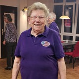 Hilde Tscharntke steht mit einem lilafarbenen T-Shirt auf einer Tanzfläche und lächelt 