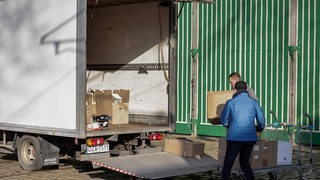 Zwei Männer beladen einen Laster