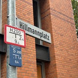Aus einem Straßenschild steht "Hillmannplatz".