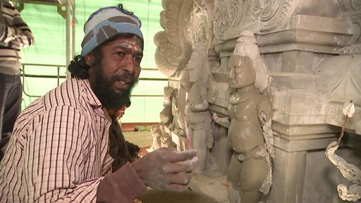 Ein Mann modeliert eine Statur mit verschiedenen Figuren für einen Hindu-Tempel.