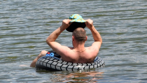 Ein Mann lässt sich in einem Schwimmring auf einem See treiben.