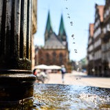 Im Vordergrund ein Brunnen in der Bremer Innenstadt. Im Hintergrund der St. Petri Dom.