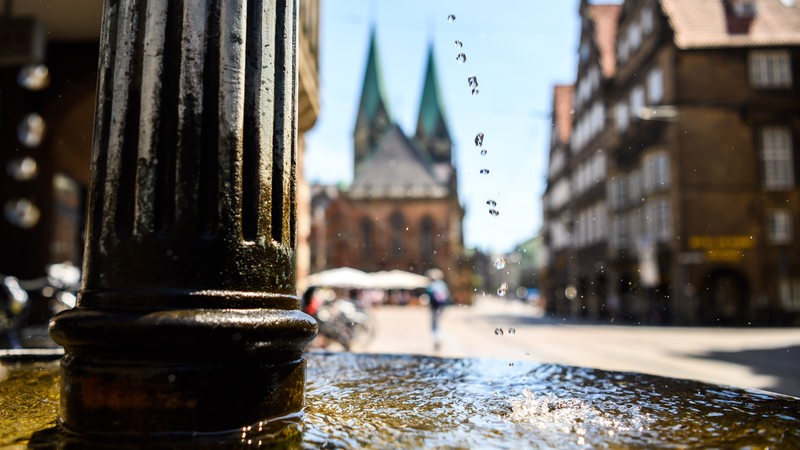 Im Vordergrund ein Brunnen in der Bremer Innenstadt. Im Hintergrund der St. Petri Dom.