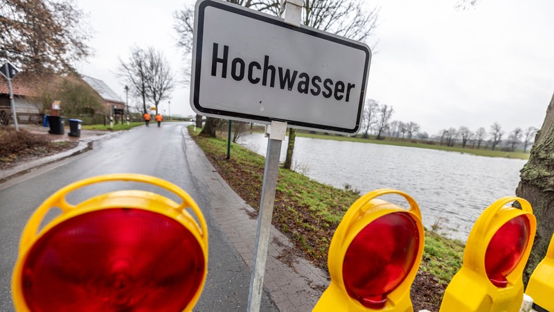 Auf einem Schild steht "Hochwasser" davor steht eine Absperrung