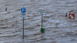 Ein Schild im Wasser warnt vor Flut.