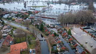 Häuser im Hochwassergebiet in der Gemeinde Lilienthal bei Bremen. Weil das überflutete Gebiet zu groß ist, um erfolgreich abzupumpen, errichten Feuerwehrleute eine Barriere mit Sandsäcken. So wird ein Teil der überfluteten Fläche abgetrennt. 
