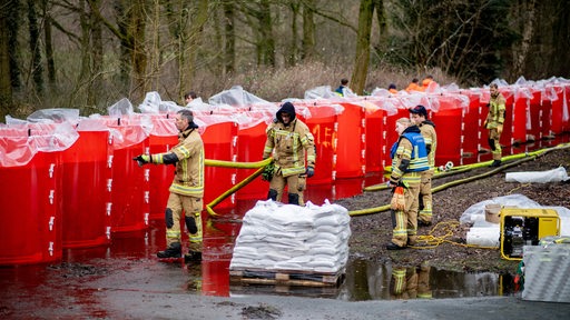 Einsatzkräfte der Feuerwehr befüllen ein mobiles Deichsystem in Oldenburg
