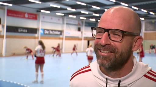 Der neue Trainer des Bremer Hockey Clubs Florian Keller lächelnd in der Trainingshalle beim Interview.