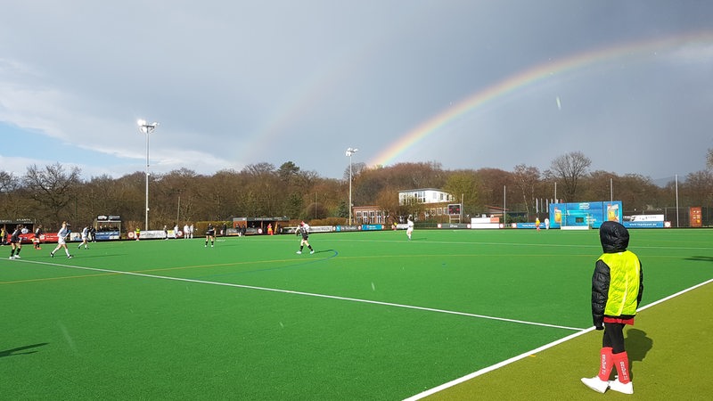 Ein Doppel-Regenbogen erstrahlt in der Sonne über dem Hockey-Feld des Bremer Hockey-Clubs während eines Länderspiels.