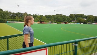 Hockey-Spielerin Lena Frerichs schaut nachdenklich auf den Platz, auf dem sie sich den Kreuzbandriss zugezogen hat.