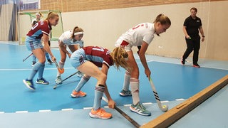 Spielerinnen des Bremer HC verteidigen beim Bundesliga-Spiel in der Halle den Ball gegen Hamburger Spielerinnen.