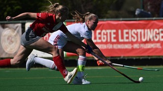 Die Bremer Hockey-Spielerin Lena Frerichs ist auf dem Feld im Zweikampf mit ihrer Gegnerin vom Club an der Alster.