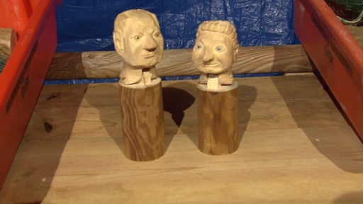 Zwei Köpfe aus Holz geschnitzt.