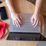 Hände liegen auf Laptop und tippen