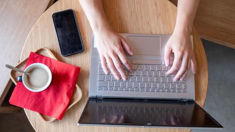 Hände liegen auf Laptop und tippen