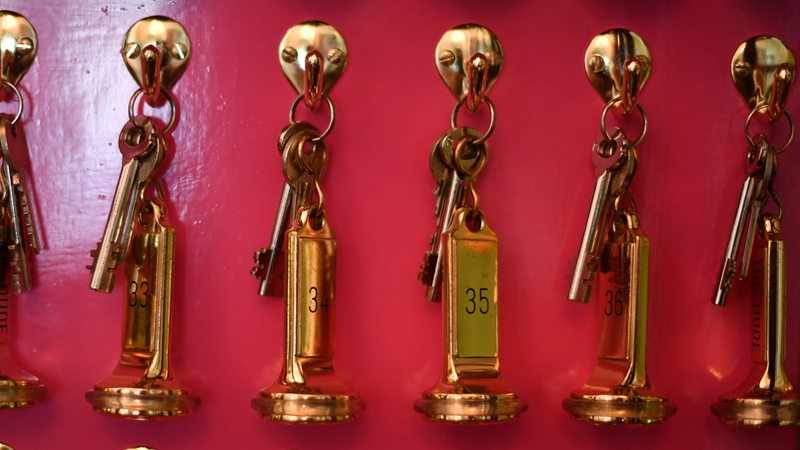 Zimmerschlüssel hängen in einem Schlüsselkasten an der Rezeption eines Hotels
