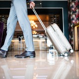 Ein Mann geht durch eine Hotellobby und zieht dabei einen Koffer hinter sich her.