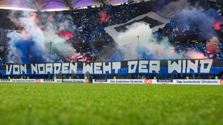 Fans des Hamburger SV zünden Rauch im Stadion und zeigen ein Banner mit dem Text: "Von Norden weht der Wind."