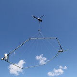 Ein Hubschrauber fliegt im Himmel und zieht ein sechseckiges Gestell 